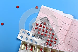 Medical cardiology concept. Heart health pills and cardiogram on a blue background. ECG. Copy space