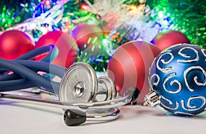 Medical Christmas and New Year photo - stethoscope or phonendoscope are located near balls for Christmas tree in blurry background