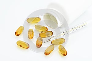 Medical : Close up of Omega 3 Capsules with Bottle and Analog Thermometer on White Background Shot in Studio.