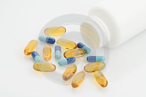 Medical : Close up of Yellow and Blue Capsules with Bottle on White Background Shot in Studio.