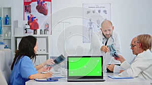 Medical colleagues working in hospital office using laptop with mock-up display