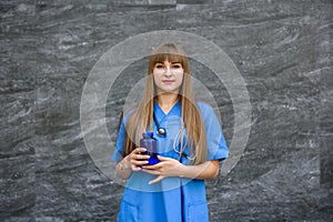Medical concept. Beautiful young nurse in blue uniform holds pills