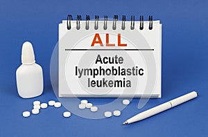 On a blue background, a pen, tablets and a notepad with the inscription - ALL Acute lymphoblastic leukemia photo