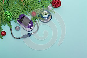 Medical concept: celebrating Christmas in healthcare. Top view of a flat lay close-up of a stethoscope, pulse oximeter
