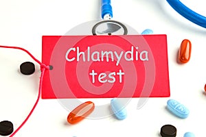 Medical concept. Chlamydia Test text on a red card on a white background, next to a stethoscope and pills, vitamins