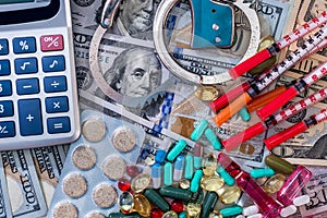 Medical concept on dollar background, pills, syringes and handcuffs