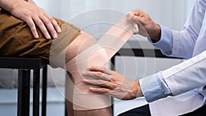 Medical concept a male doctor putting a bandage on knee`s male patient after his accident