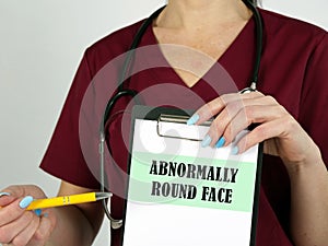 Medical concept meaning ABNORMALLY ROUND FACE with sign on the piece of paper