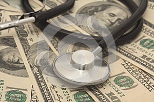 Medical concept - stethoscope over the dollar bills