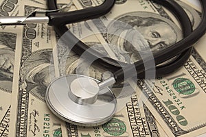 Medical concept - stethoscope over the dollar bills