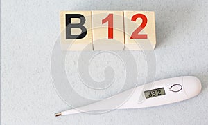 Medical concept - thermometer and wooden cubes with the text Vitamin B12