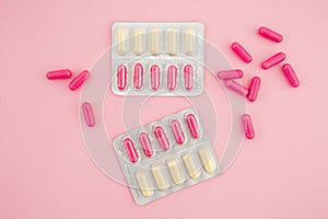 Medical concept with vitamins pills and white flowers on pink background. Flat lay, top view.