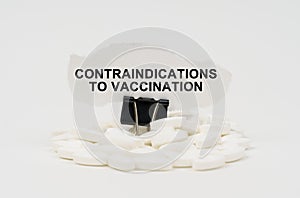 On a white surface are pills and torn paper with the inscription - contraindications to vaccination photo