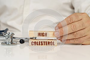 On a white surface, a stethoscope and wooden plates with the inscription - High colesterol photo