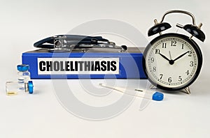 On a white surface, a thermometer, a stethoscope and a folder with the inscription - Cholelithiasis photo