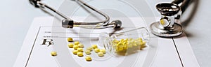 Medical concept. Yellow pills with stethoscope, pills, notepad, medical prescription on the doctor desktop. Treating a patient