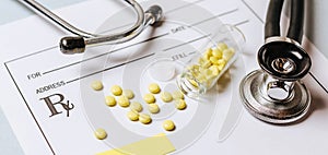 Medical concept. Yellow pills with stethoscope, pills, notepad, medical prescription on the doctor desktop. Treating a patient