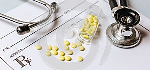 Medical concept. Yellow pills with stethoscope  pills  notepad  medical prescription on the doctor\'s desktop