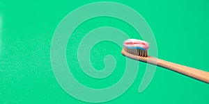 Medical conception of bamboo natural toothbrush with natural bristles on a greenbackground. Free copy space