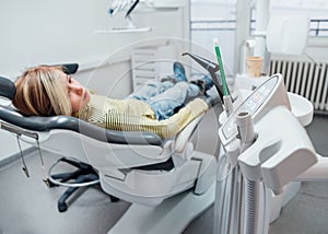 Medical dental chair vacuum instruments photo. Little girl sitting in stomatology clinic chair after teeth dental procedures.