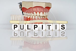 Medical, dental concept. The text is written on the cubes - PULPITIS. In the background is a model of the jaw, with a toothbrush