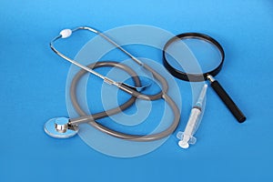 Medical device for listening stethoscope, heart, magnifier, syringe for injection on a blue background, medical research and