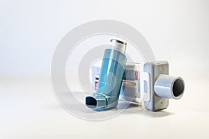 Medical devices for lung diseases like asthma, allergy and COPD, peak flow meter and blue inhaler pump spray on a light gray