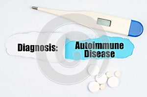 Medical diagnosis. On paper a thermometer, pills and a hole, inside which the inscription - Autoimmune Disease photo