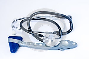 Medical diagnostic equipment - stethoscope and neurological reflex rubber hammer lying on a white table in the office of a doctor