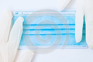 Medical disposable blue mask and a pair of white latex gloves lie on a white background.