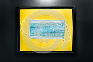 Medical disposable mask in a frame. Exhibition of a medical mask in a showroom. The concept of coronavirus, covid-19 and means of