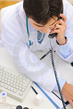 Medical doctor dialing phone number. Upper view