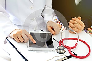 Medical doctor discusses with patient about the health examination results by using tablet computer.