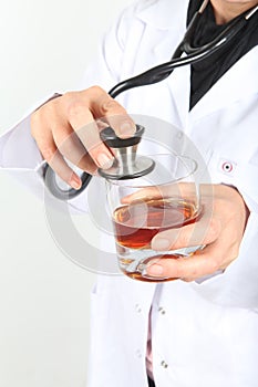 A medical doctor holding a glass of Whisky