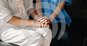 Medical doctor holing senior patient`s hands and comforting her at home