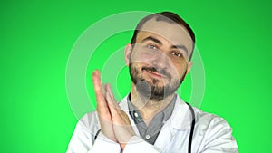 Medical doctor man looking at camera, congratulates on recovery and applauds. Green background