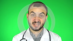 Medical doctor man looking at camera and explaining something. green screen background