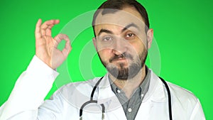 Medical doctor man looking at camera and showing okay gesture. Green screen background