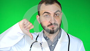 Medical doctor man looking at camera and showing thumb down. Green screen background