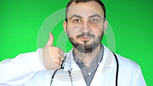 Medical doctor man looking at camera and showing thumb up. Green screen background