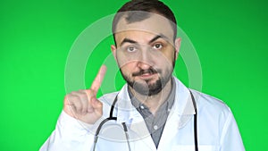 Medical doctor man looking at camera and waving finger to reject. Green screen background