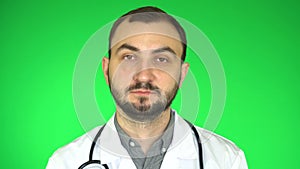 Medical doctor man looking at camera waving head yes positive answer approval, green background,