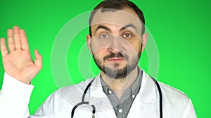 Medical doctor man looking at camera and waving his hand, greeting. Green screen background