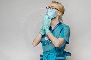 Medical doctor nurse woman wearing protective mask and latex gloves - praying nad hoping gesture