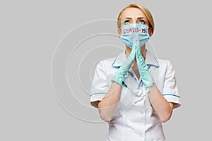 Medical doctor nurse woman wearing protective mask and latex gloves - praying nad hoping gesture