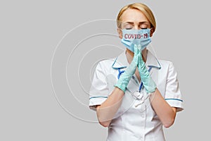 Medical doctor nurse woman wearing protective mask and latex gloves - praying nad hoping gesture