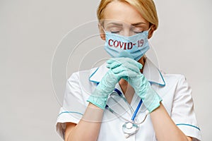 Medical doctor nurse woman wearing protective mask and latex gloves - praying nad hoping gesture