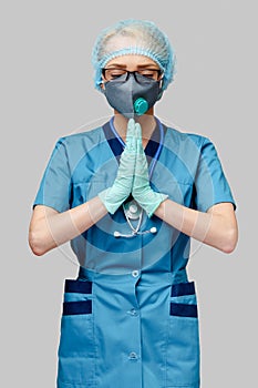 Medical doctor nurse woman wearing protective mask and latex gloves - praying nad hoping gesture