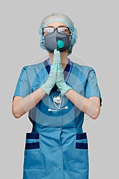 Medical doctor nurse woman wearing protective mask and latex gloves - praying nad hoping gesture