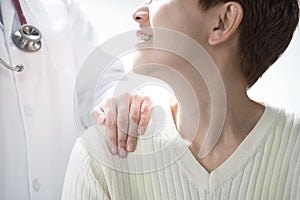 Medical doctor reassuring senior patient and putting a hand on patientâ€™s shoulder